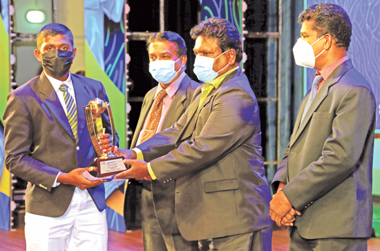 Vishwa Lahiru Kumara of Sri Sumangala College, Panadura receiving the Division II Best Bowler Award from Gamini Jayalath the Editor in Chief of Dinamina